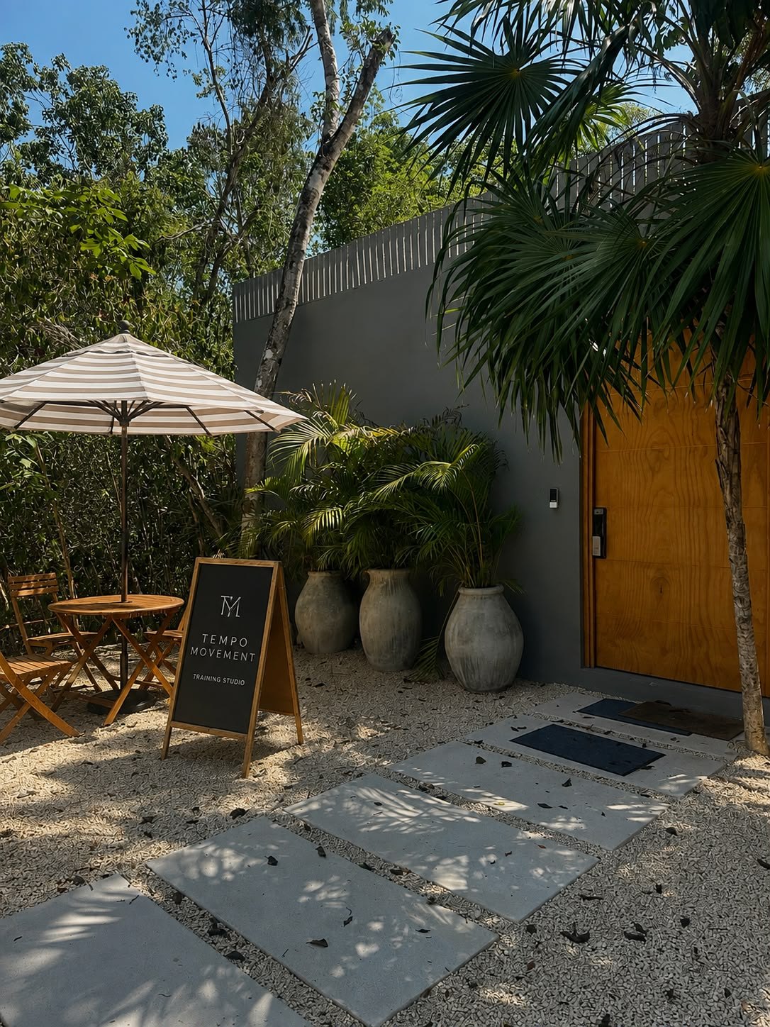 Entrada del estudio Tempo Movement en Tulum, entre palmas y grava blanca